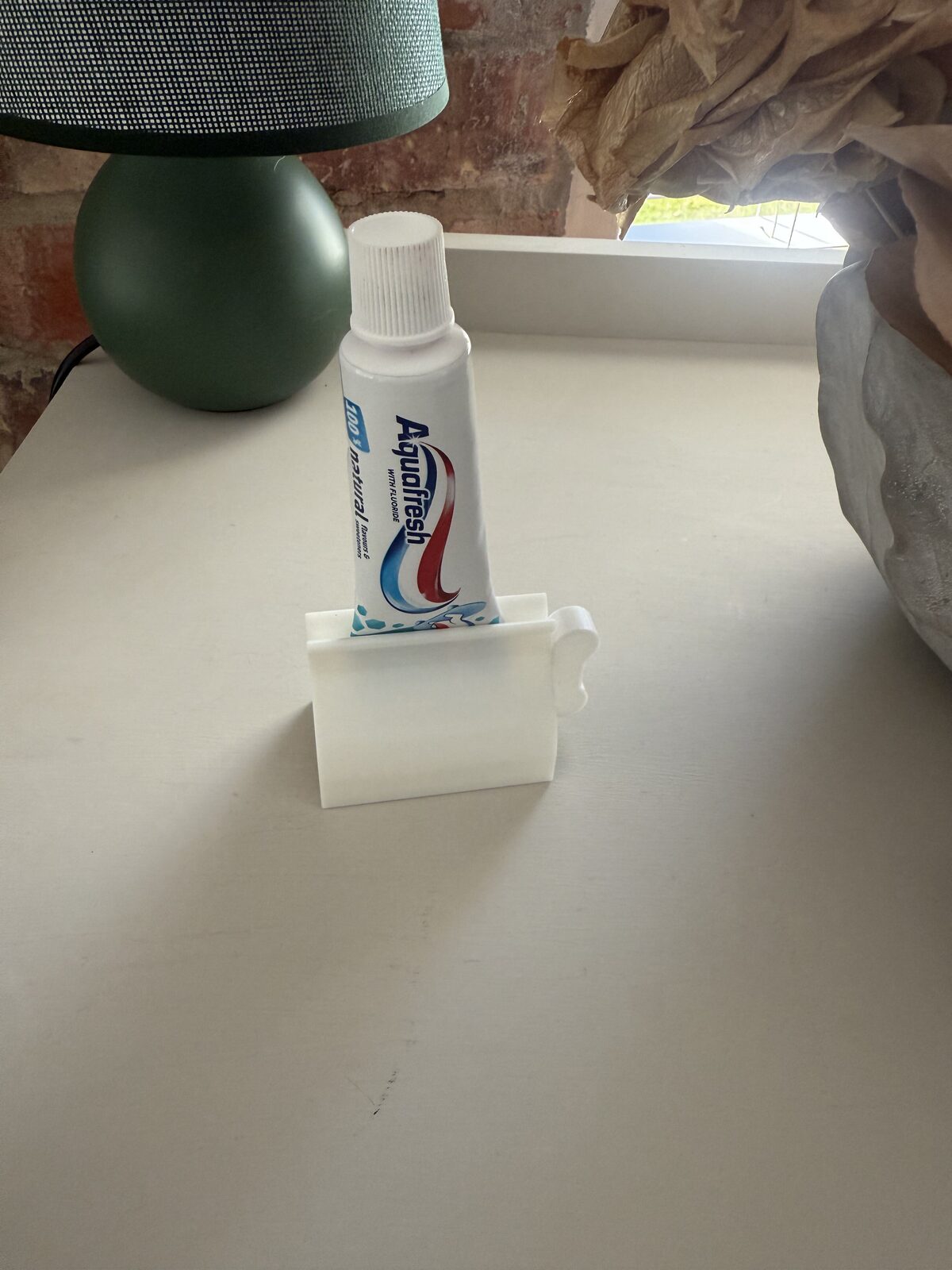 3D-printed toothpaste holder with a tube inserted